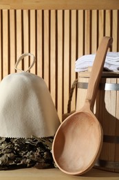 Photo of Oak sauna whisk, felt wool hat, towels, bucket and ladle on wooden surface