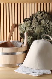 Sauna equipment. Felt wool hat, towels, oak whisk, bucket and ladle on wooden surface