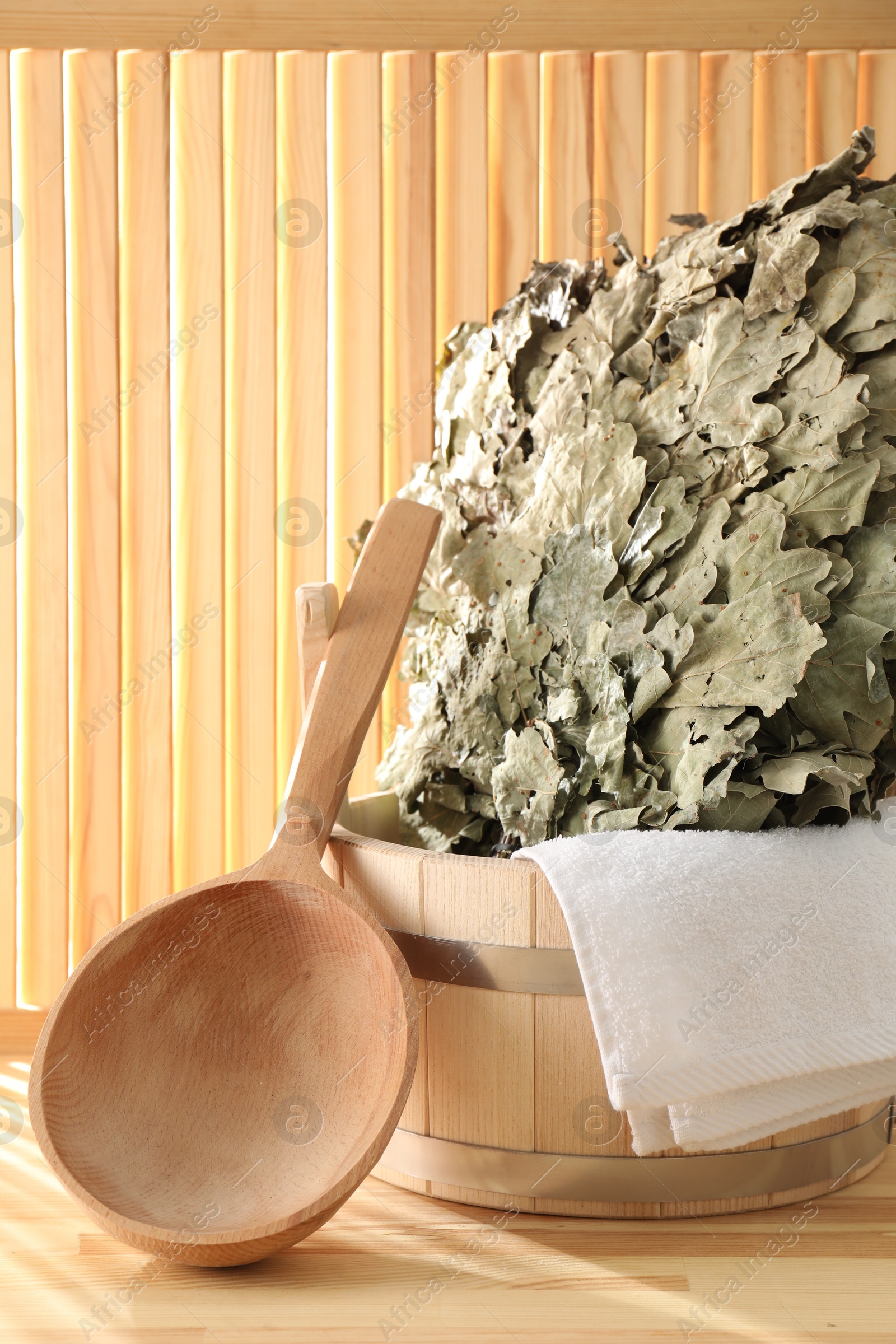 Photo of Sauna equipment. Bucket, ladle, towel and oak whisk on wooden surface