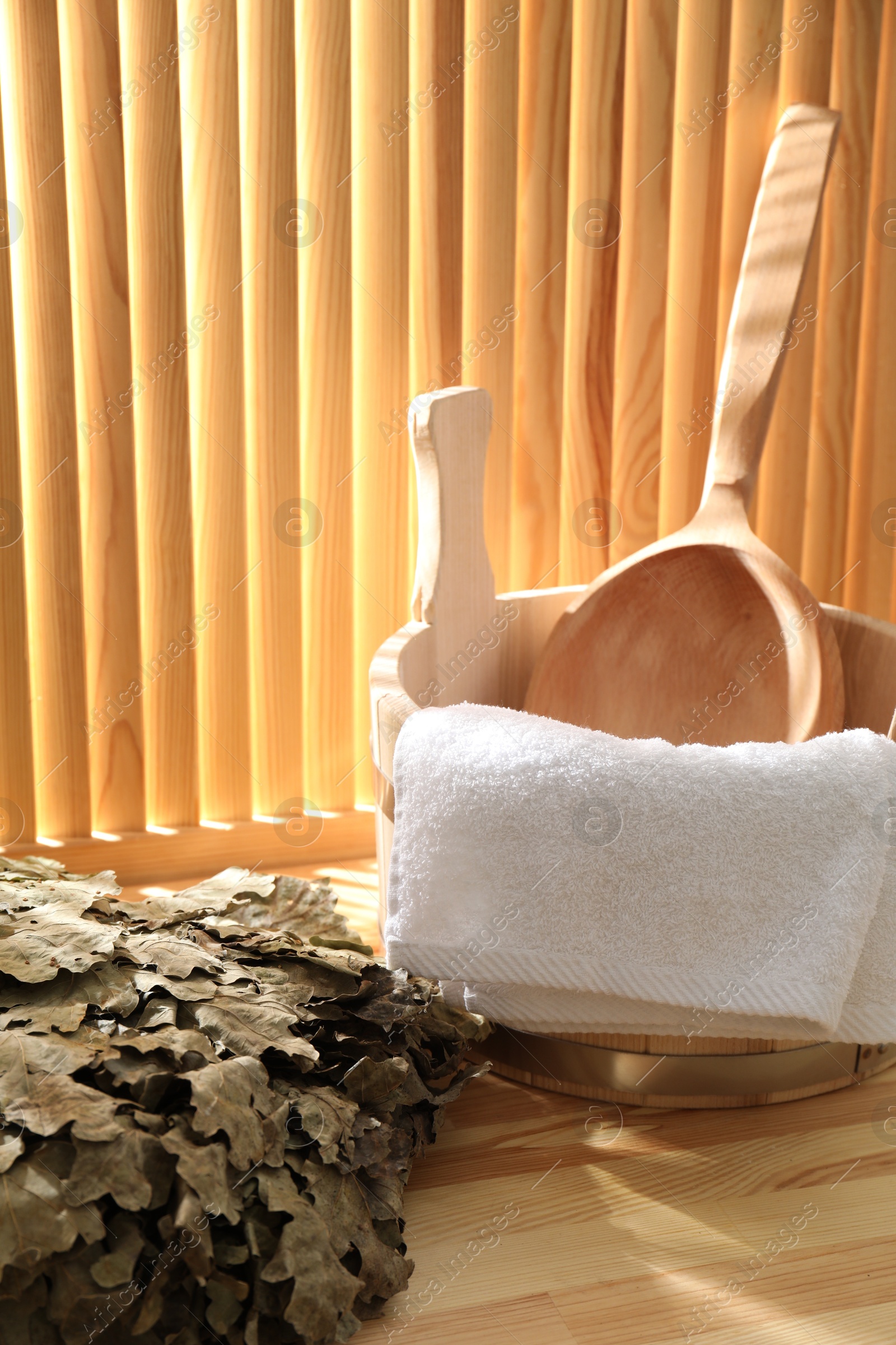 Photo of Sauna equipment. Bucket, ladle, towel and oak whisk on wooden surface