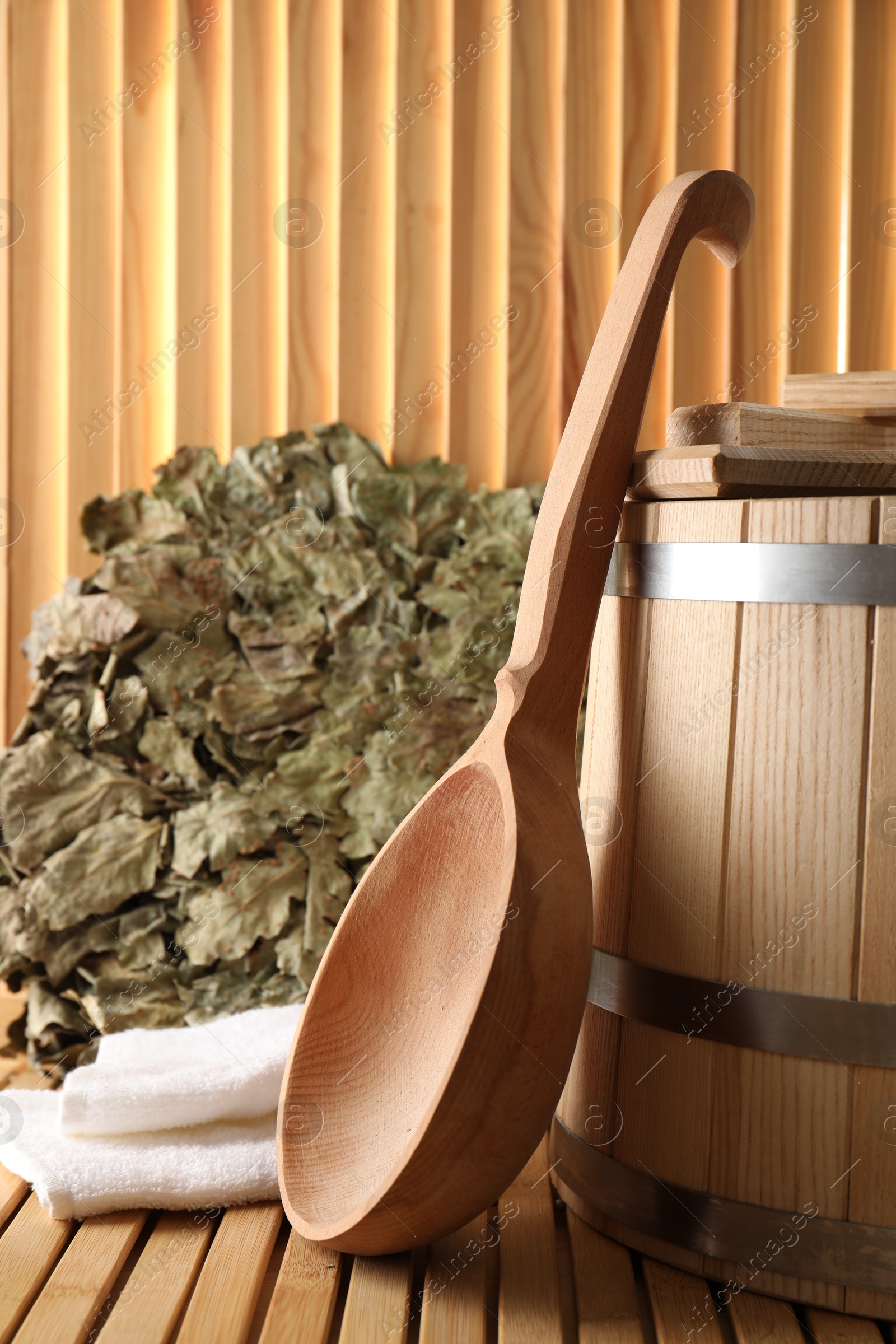 Photo of Sauna equipment. Bucket, oak whisk, towel and ladle on wooden surface