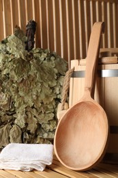 Sauna equipment. Bucket, oak whisk, towel and ladle on wooden surface