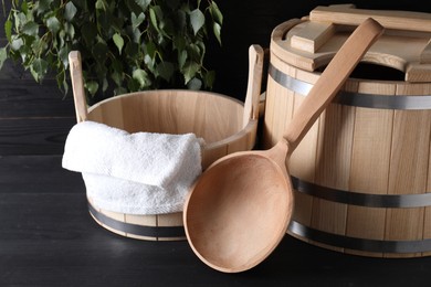 Photo of Sauna equipment. Wooden buckets, towel and ladle on black surface