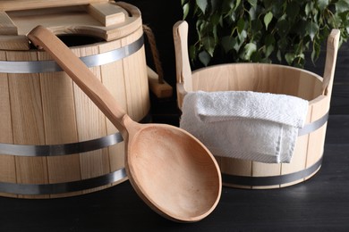 Photo of Sauna equipment. Wooden buckets, towel and ladle on black surface