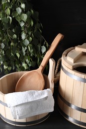 Sauna equipment. Wooden buckets, towel and ladle on black surface