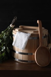 Sauna equipment. Bucket, towel, ladle and oak whisk on wooden table