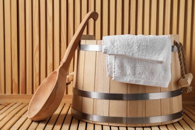 Sauna equipment. Bucket, towel and ladle on wooden surface