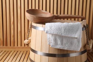 Photo of Sauna equipment. Bucket, towel and ladle on wooden surface