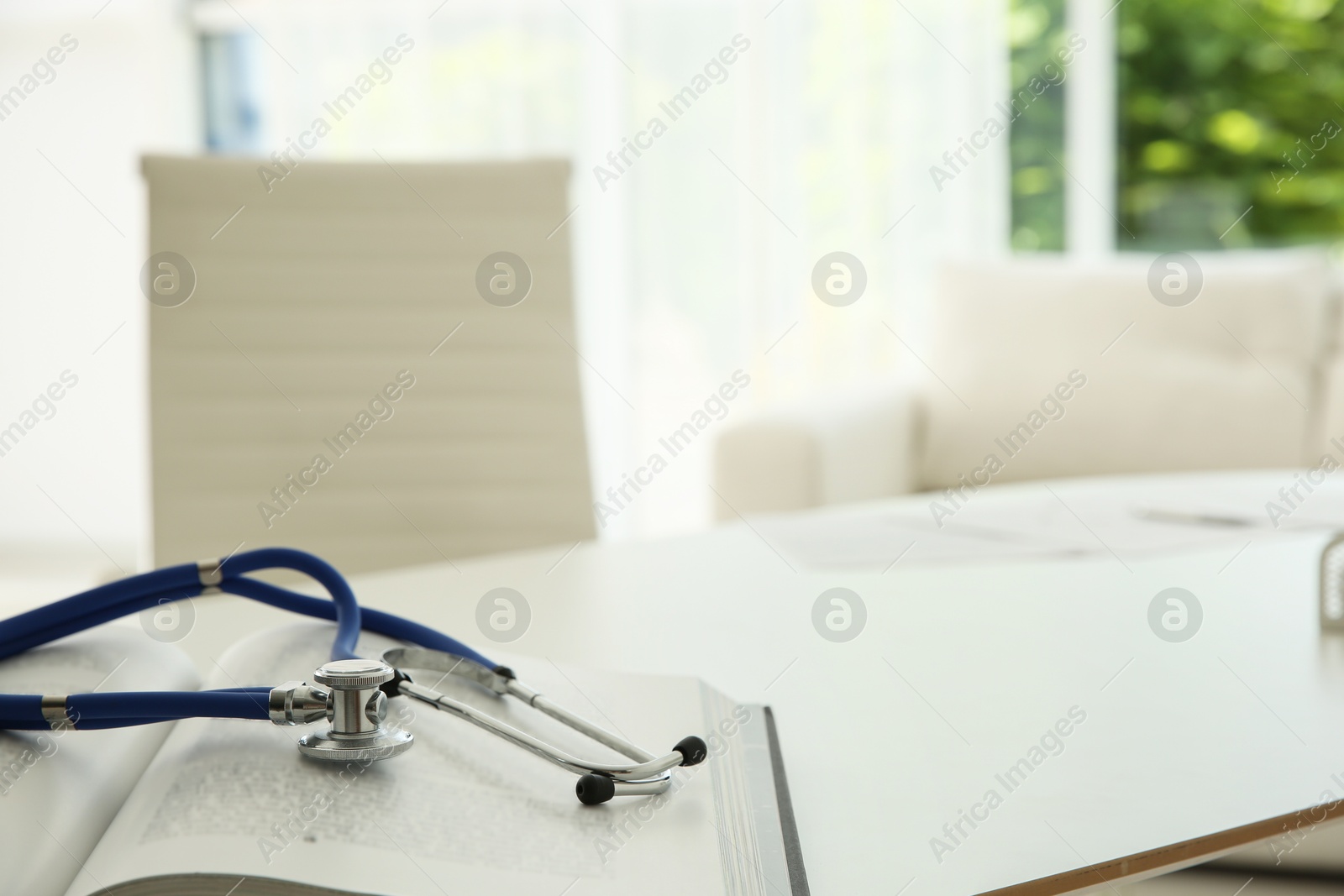 Photo of One new medical stethoscope and book on white table