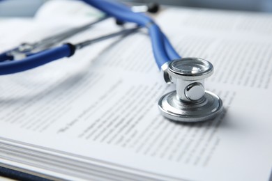 One medical stethoscope and book on table, closeup