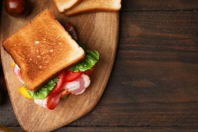 Photo of Tasty sandwiches with bacon and tomato on wooden table, top view. Space for text