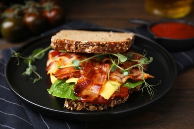 Photo of Tasty sandwich with bacon and cheese on wooden table, closeup