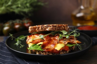 Photo of Tasty sandwich with bacon and cheese on wooden table, closeup