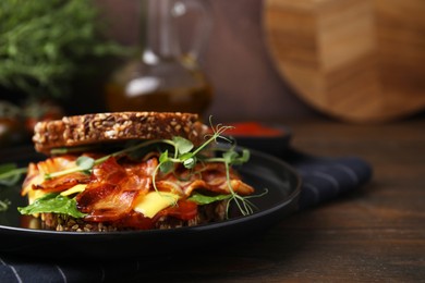 Photo of Tasty sandwich with bacon and cheese on wooden table, closeup