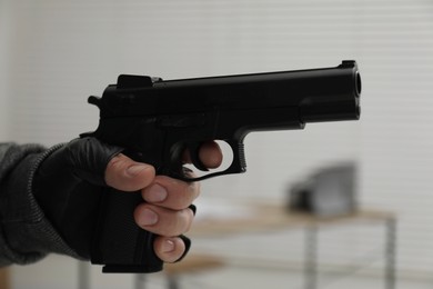 Photo of Dangerous criminal with gun indoors, closeup. Armed robbery