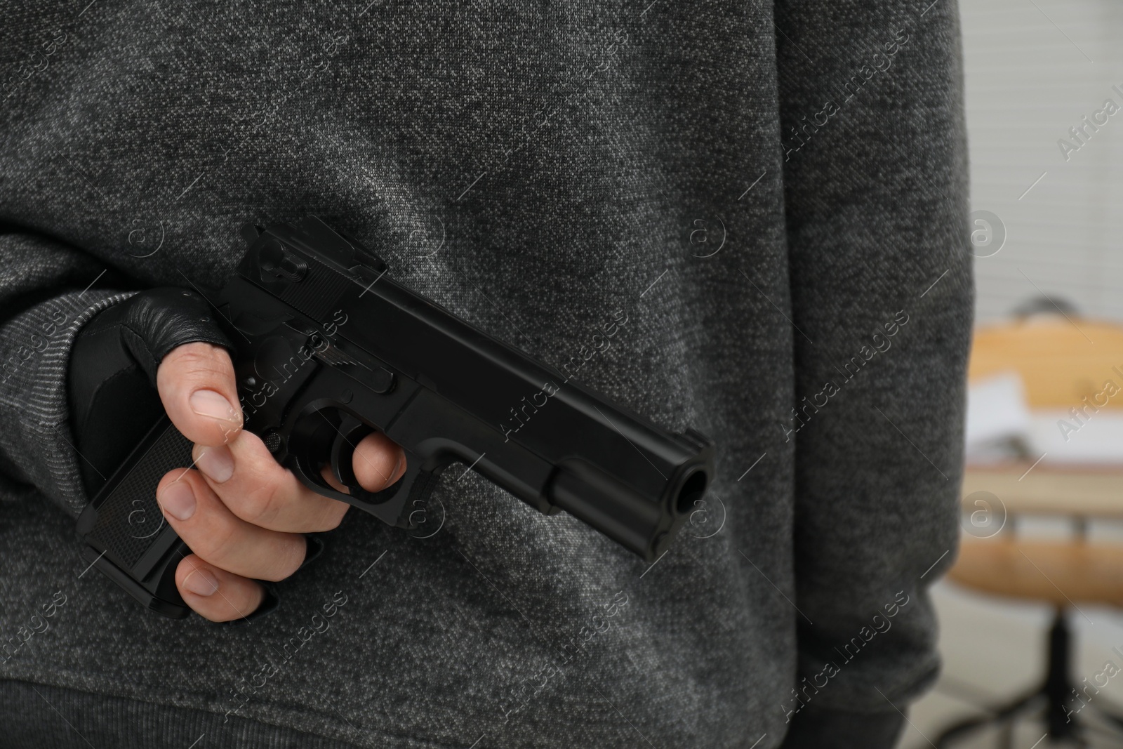 Photo of Man hiding gun behind his back indoors, closeup. Armed robbery