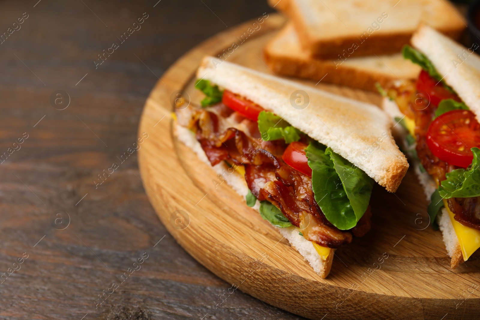 Photo of Delicious sandwiches with fried bacon on wooden table, closeup. Space for text