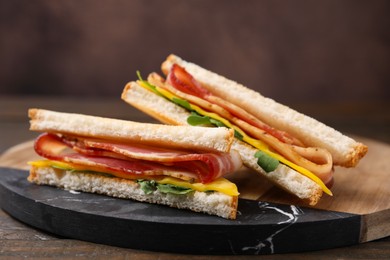 Photo of Delicious sandwiches with bacon on wooden table, closeup