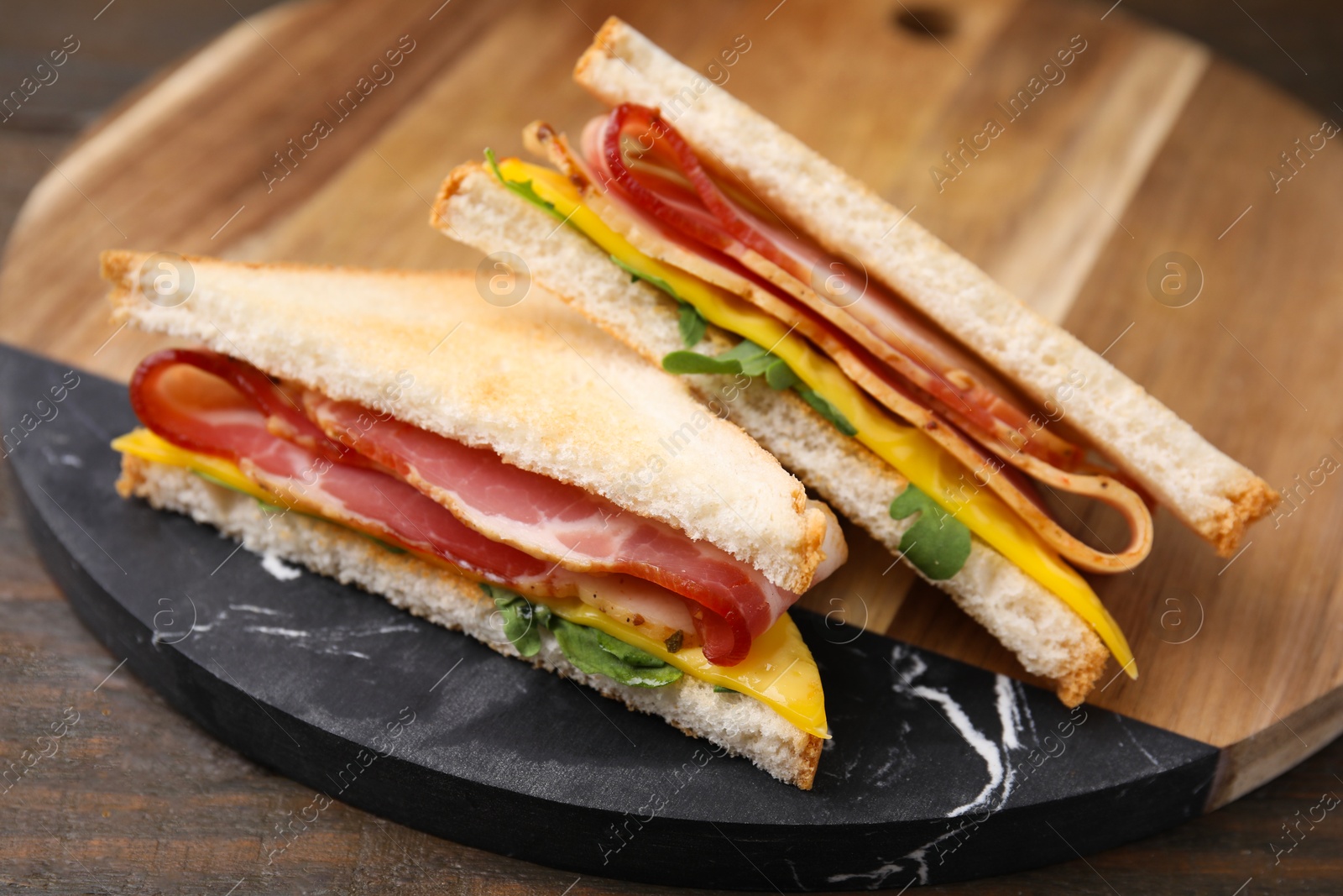 Photo of Delicious sandwiches with bacon on wooden table, closeup