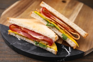 Photo of Delicious sandwiches with bacon on wooden table, closeup