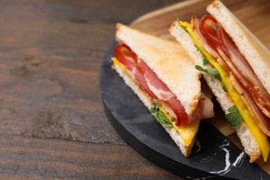 Photo of Delicious sandwiches with bacon on wooden table, closeup. Space for text