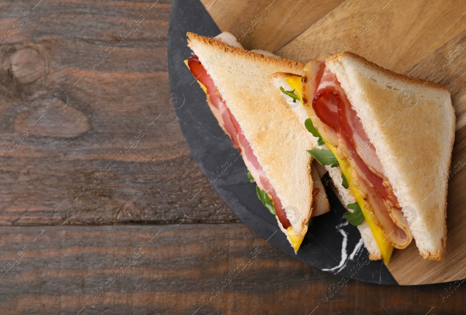 Photo of Delicious sandwiches with bacon on wooden table, top view. Space for text