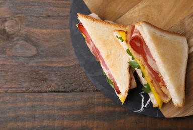 Photo of Delicious sandwiches with bacon on wooden table, top view. Space for text