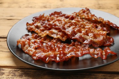 Photo of Slices of tasty fried bacon on wooden table, closeup