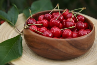 Photo of Tasty ripe red cherries in wooden bowl outdoors