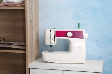 White sewing machine on nightstand near light blue wall indoors