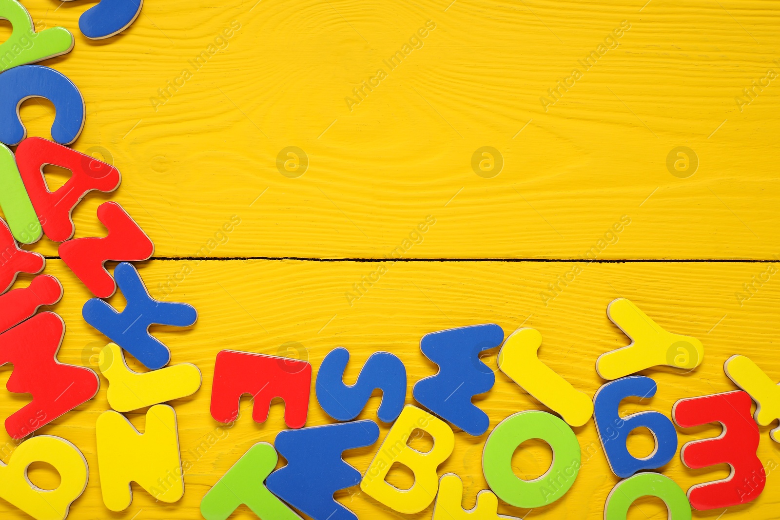 Photo of Learning alphabet. Magnetic letters on yellow wooden background, flat lay. Space for text