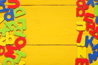 Learning alphabet. Magnetic letters on yellow wooden background, flat lay. Space for text