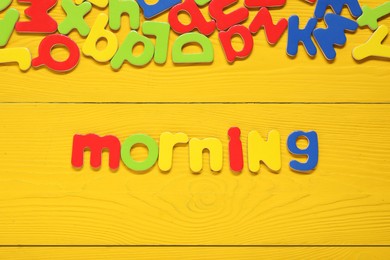 Word Morning made of magnetic letters on yellow wooden background, flat lay. Learning alphabet