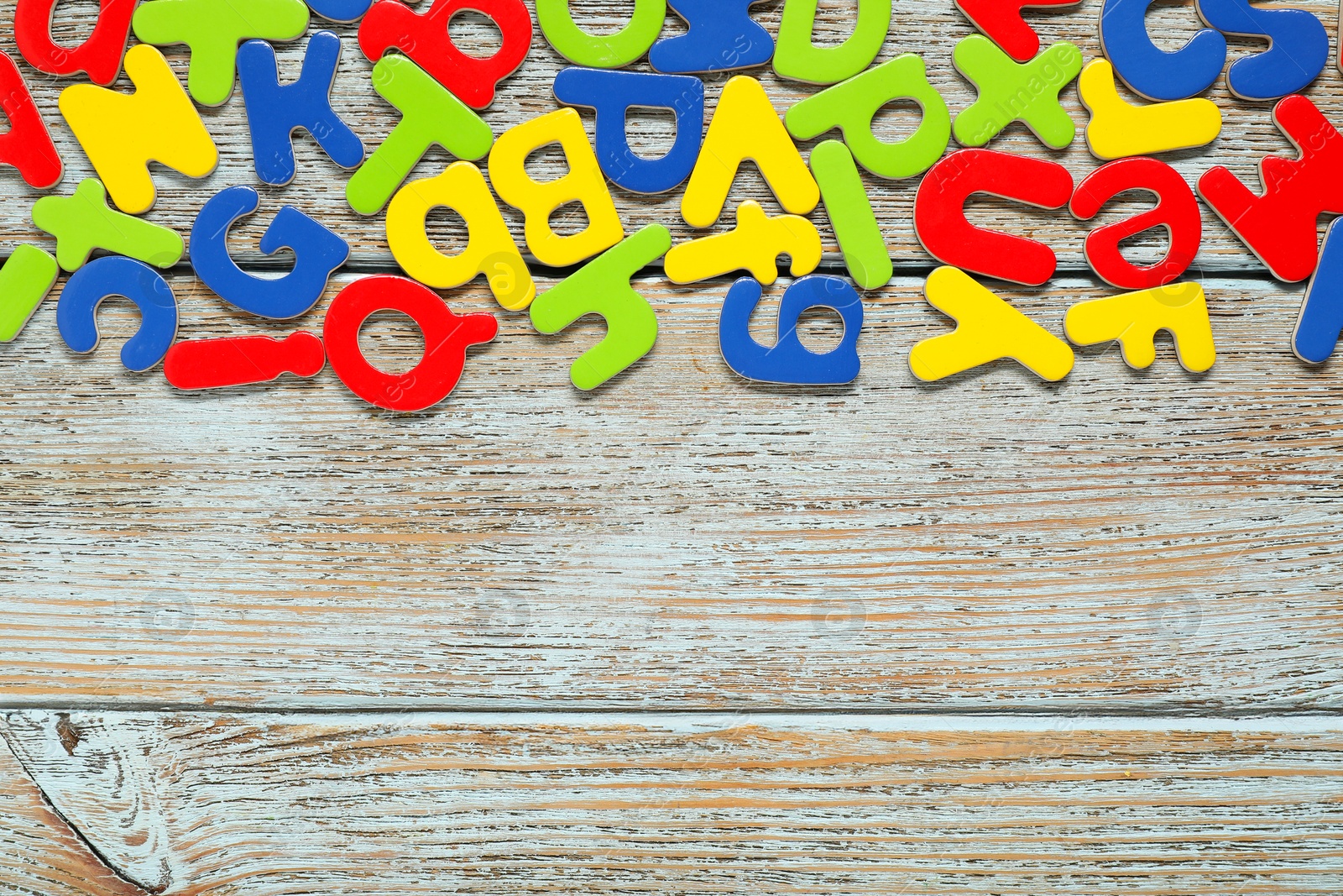 Photo of Learning alphabet. Magnetic letters on wooden background, flat lay. Space for text