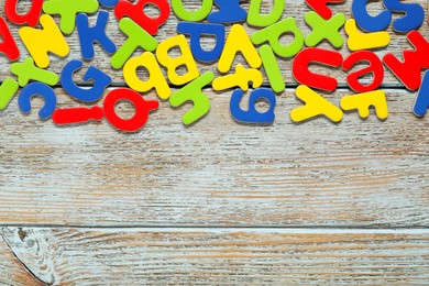 Learning alphabet. Magnetic letters on wooden background, flat lay. Space for text