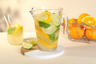 Photo of Freshly made lemonade with mint in jug and glass on beige background