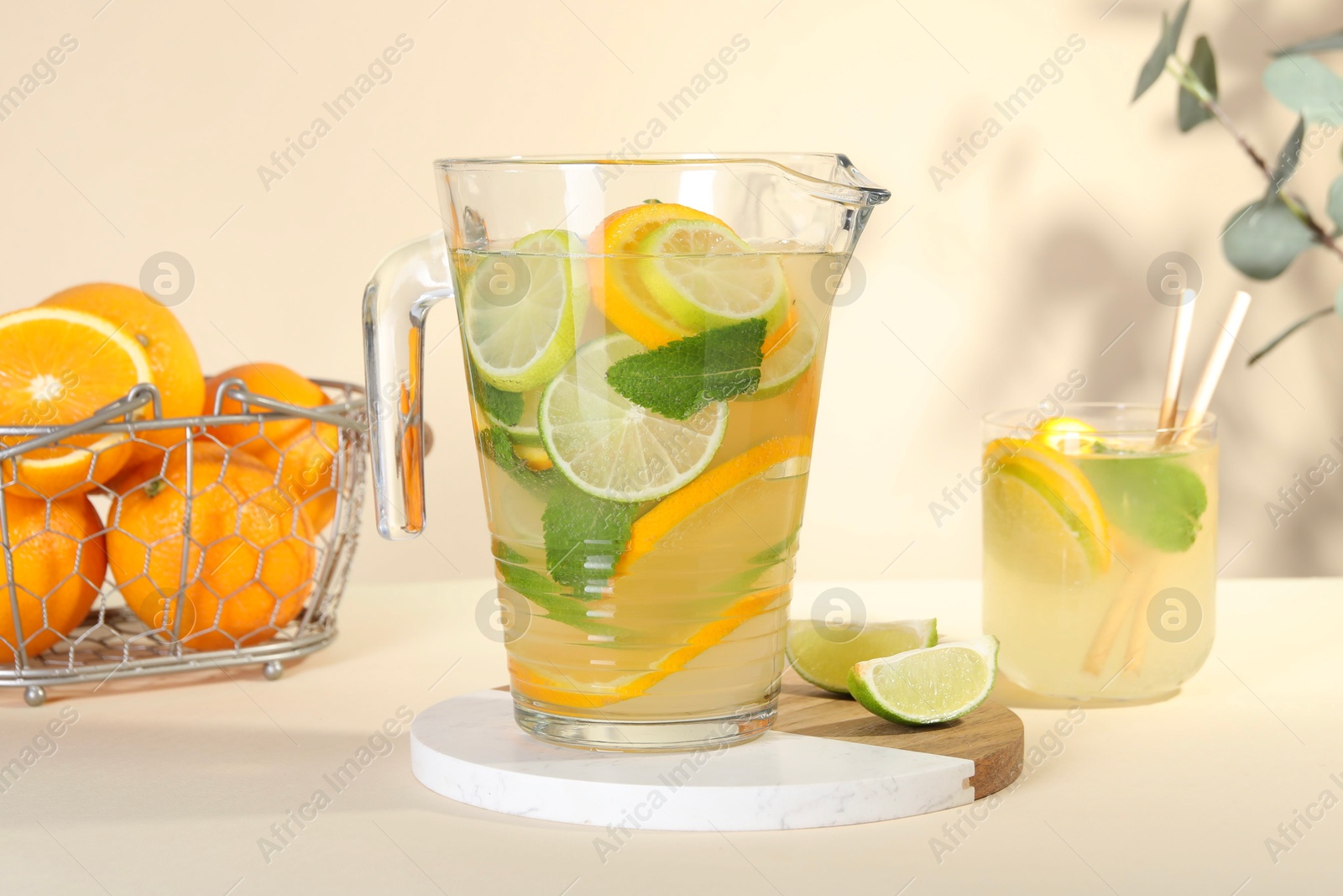 Photo of Freshly made lemonade with mint in jug and glass on beige background