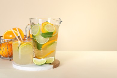 Photo of Freshly made lemonade with mint in jug and glass on beige background, space for text