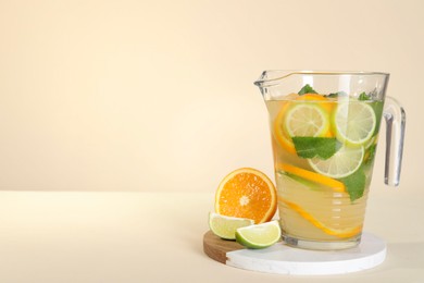 Photo of Freshly made lemonade with mint in jug on beige background, space for text