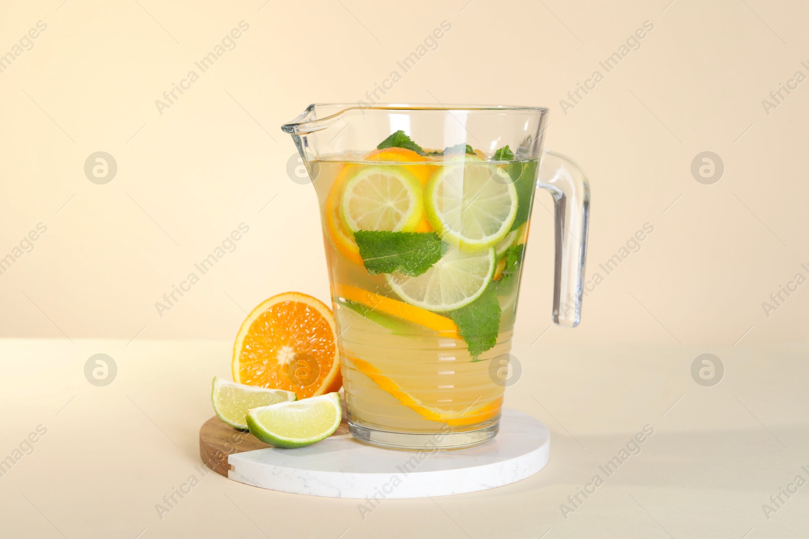 Photo of Freshly made lemonade with mint in jug on beige background