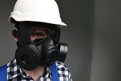Photo of Worker in gas mask and helmet on grey background. Space for text