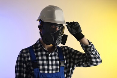 Photo of Worker in gas mask and helmet on color background