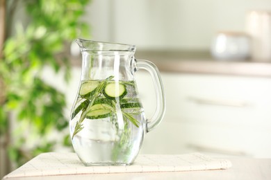 Photo of Refreshing cucumber water with rosemary in jug on white table