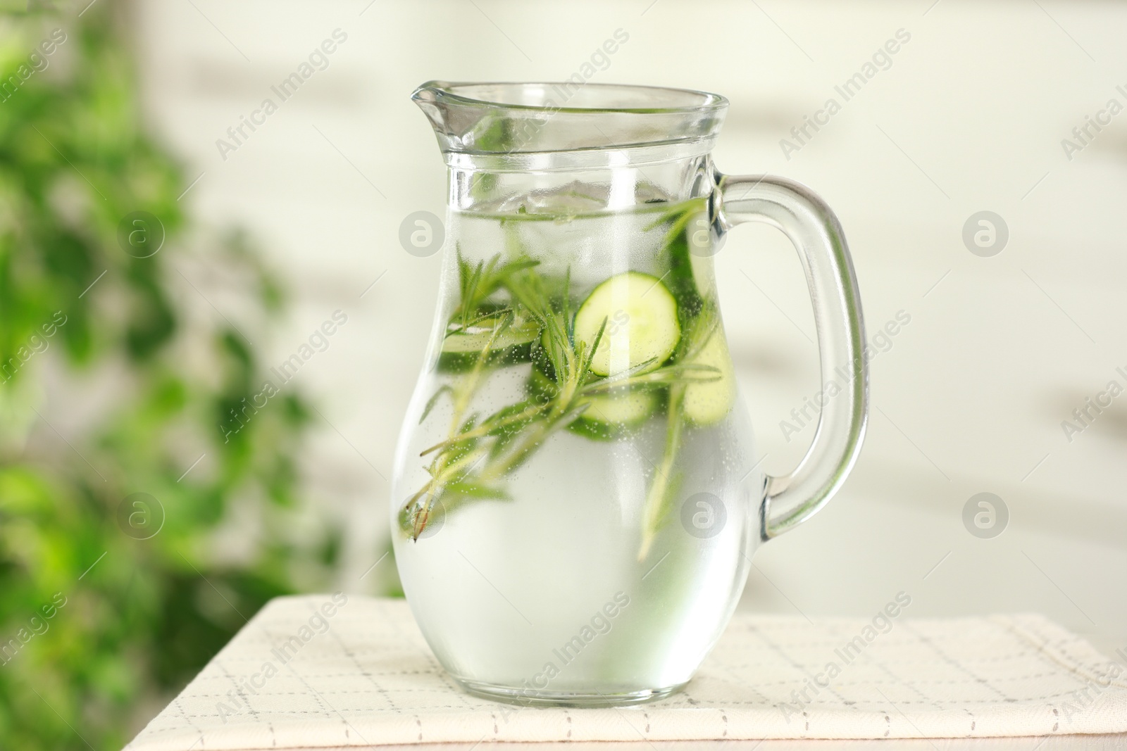 Photo of Refreshing cucumber water with rosemary in jug on white table, closeup