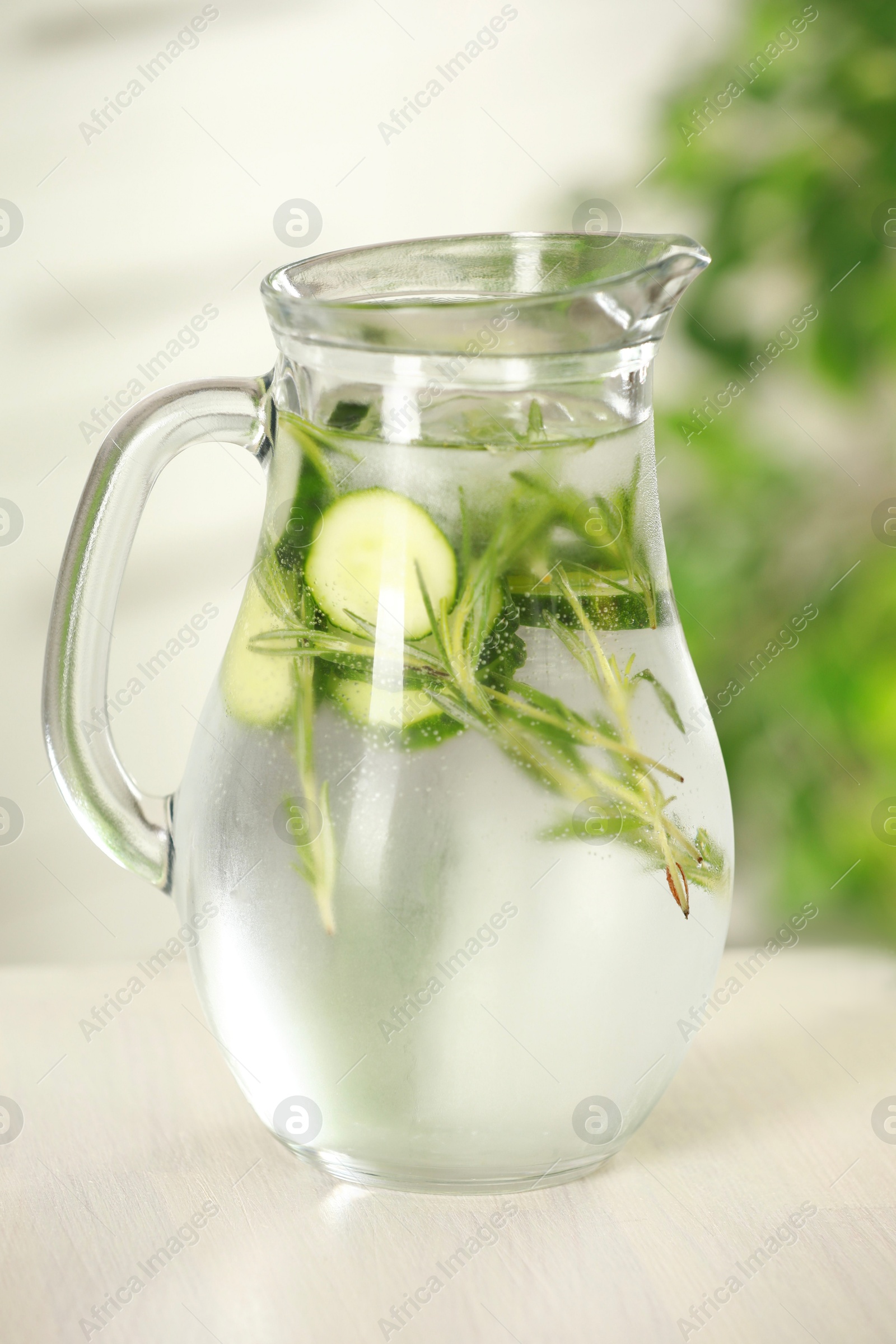 Photo of Refreshing cucumber water with rosemary in jug on white wooden table, closeup