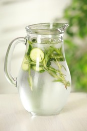 Photo of Refreshing cucumber water with rosemary in jug on white wooden table, closeup