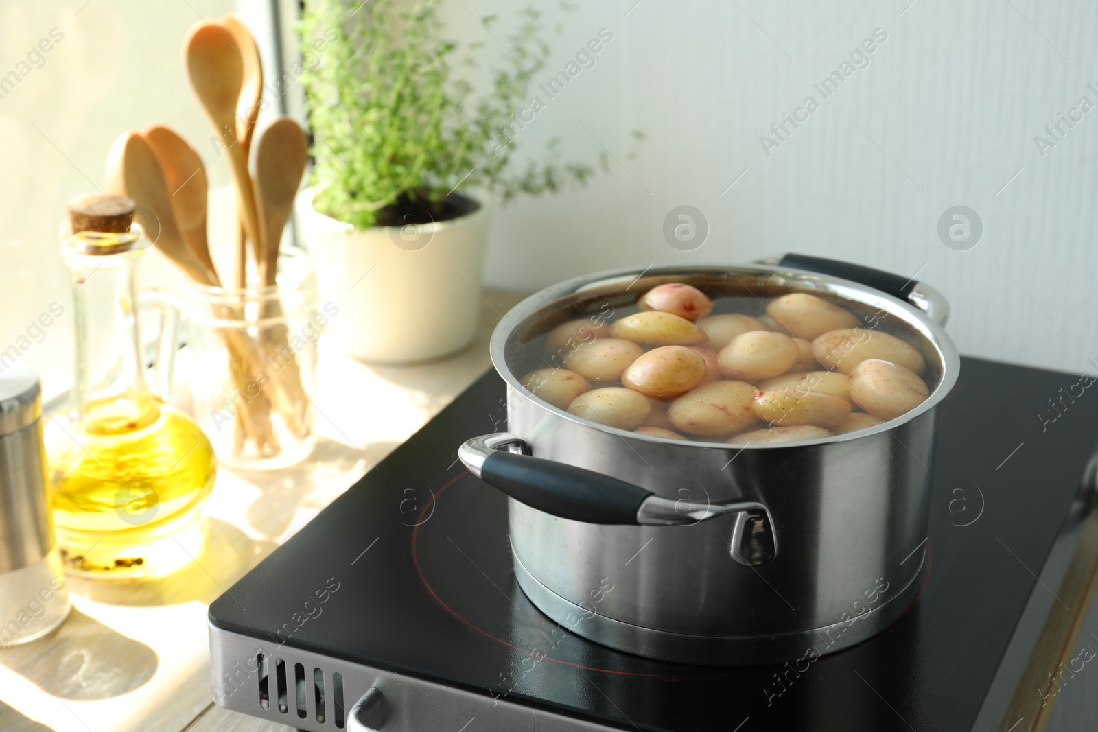 Photo of Boiling potatoes in pot on stove in kitchen