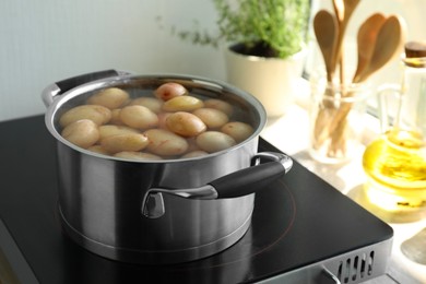 Photo of Boiling potatoes in pot on stove in kitchen