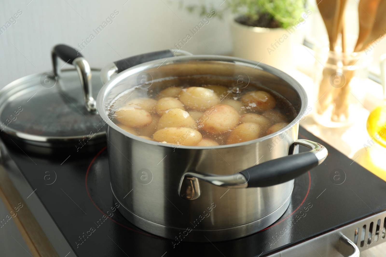 Photo of Boiling potatoes in pot on stove in kitchen