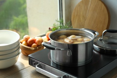 Photo of Boiling potatoes in pot on stove in kitchen